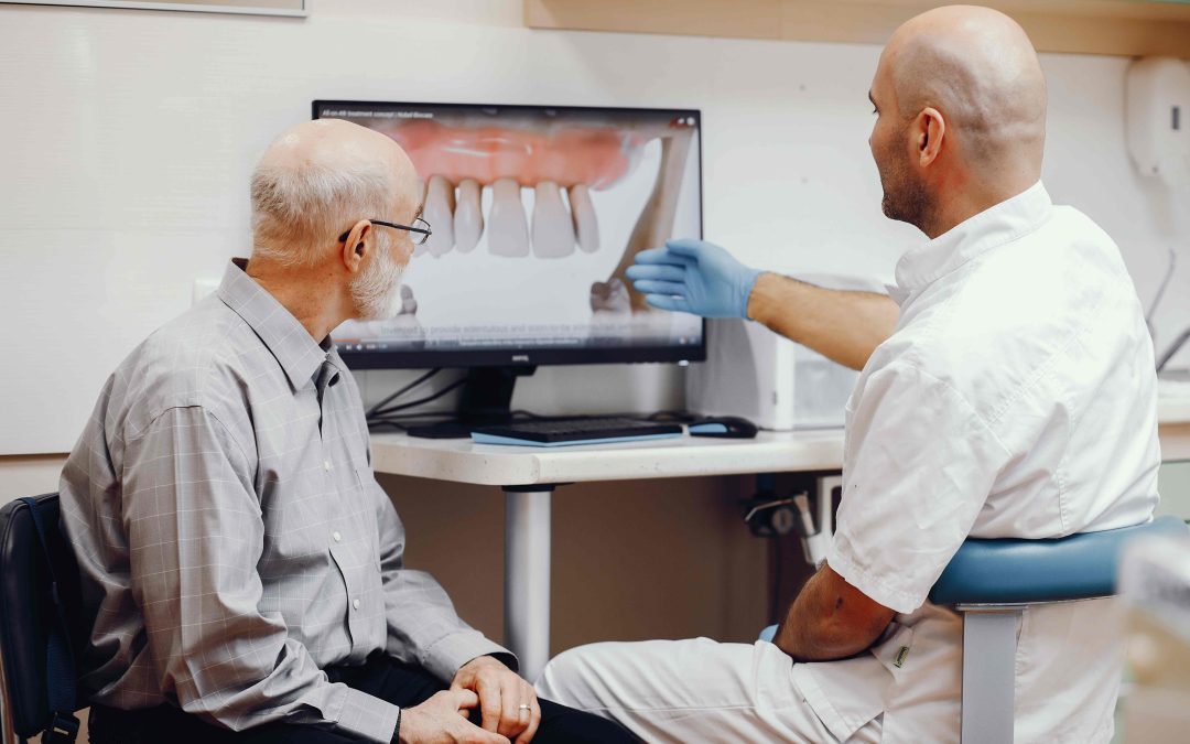 A dentist explains a dental X-ray to an elderly patient during a consultation in a modern dental clinic.